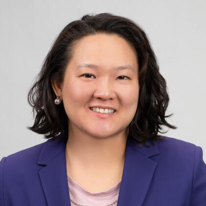 Sheila is smiling and wearing a pink top with a purple blazer.